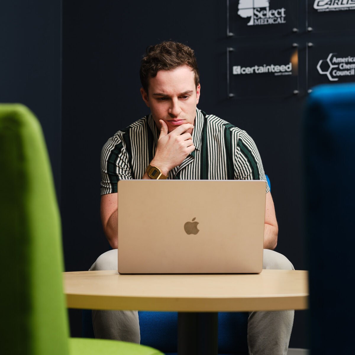 employee looking at laptop, client logos in background