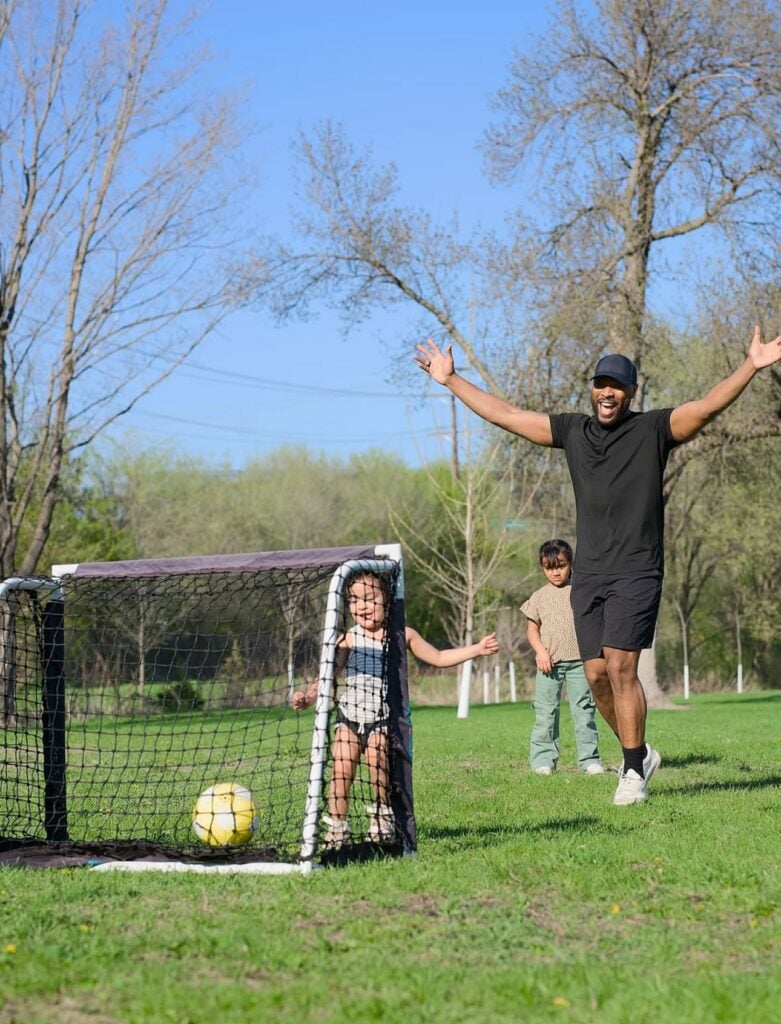 father with two young children playing soccer