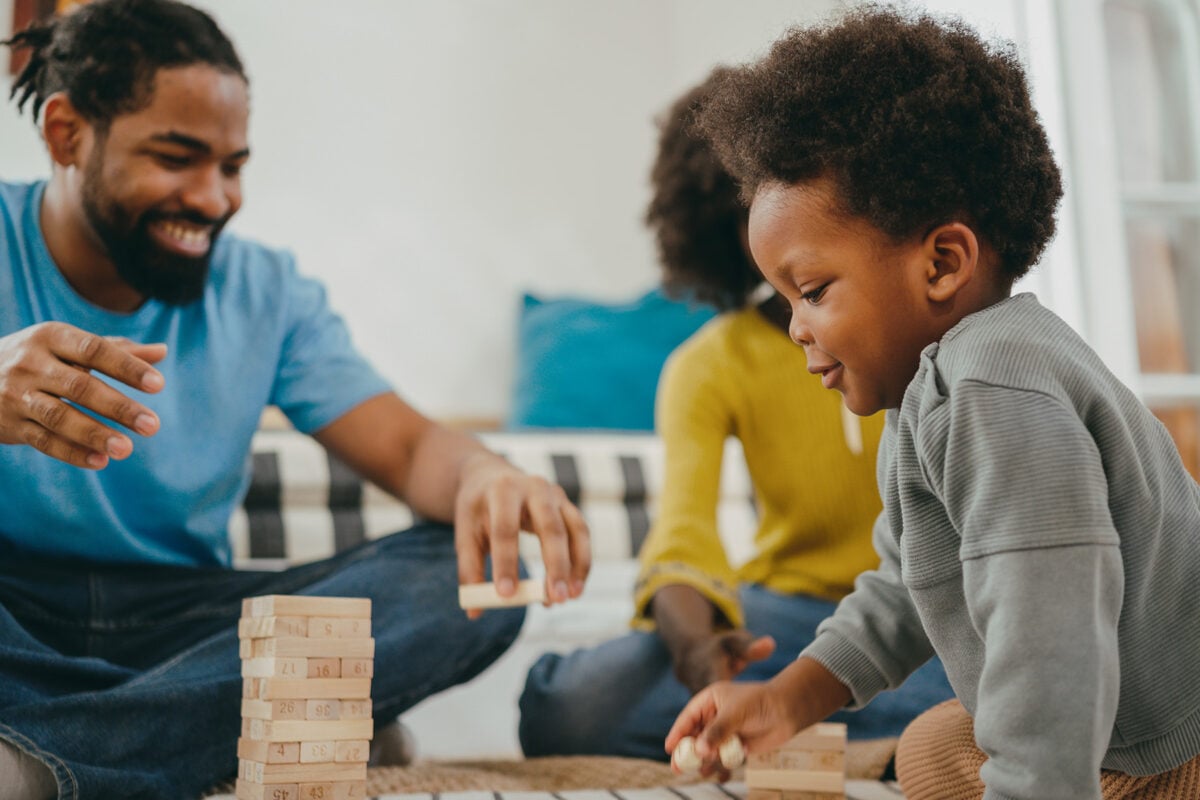 A little boy playing a game with his parents at home in a living room