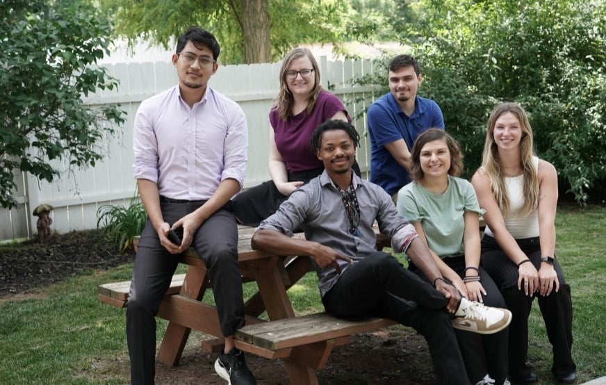 Summer 2024 interns sitting on a picnic table