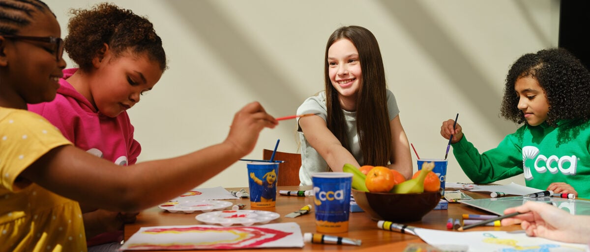 a child sitting at a table with a bowl of fruit