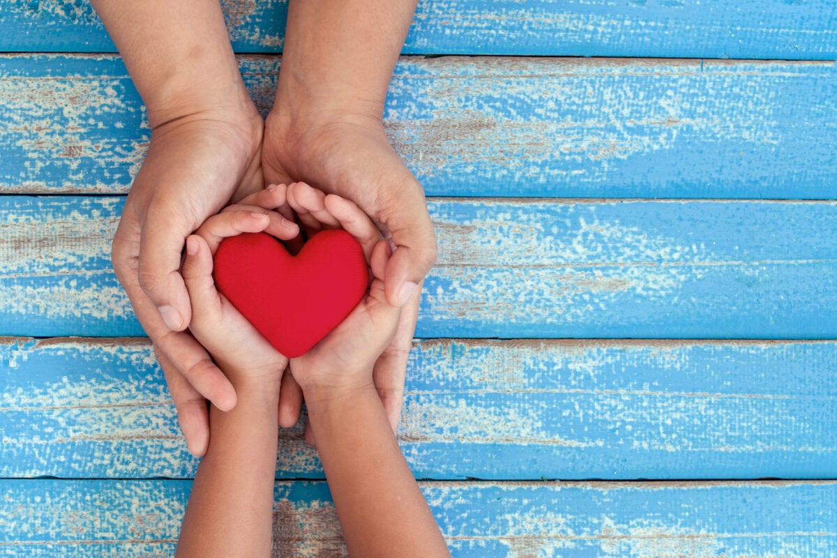 Hands holding other hands with a heart in them.