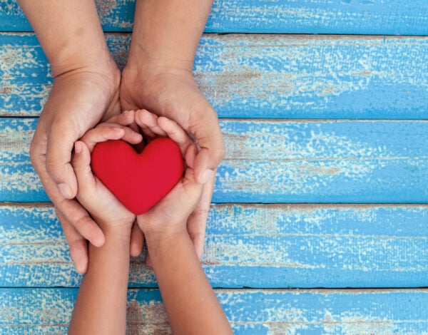 Parent and child holding an object the shape of a heart in their hands