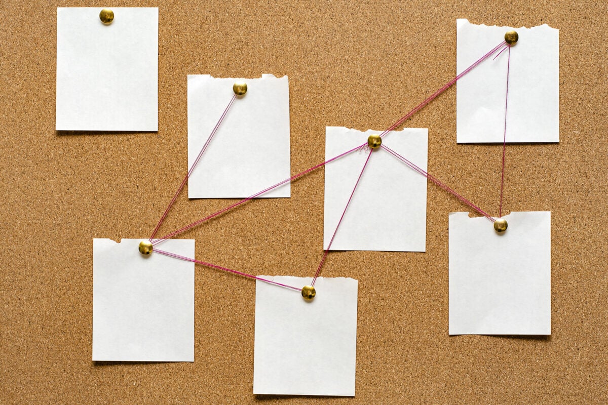 Blank paper notes are pinned to a cork board. The concept of detective investigation.