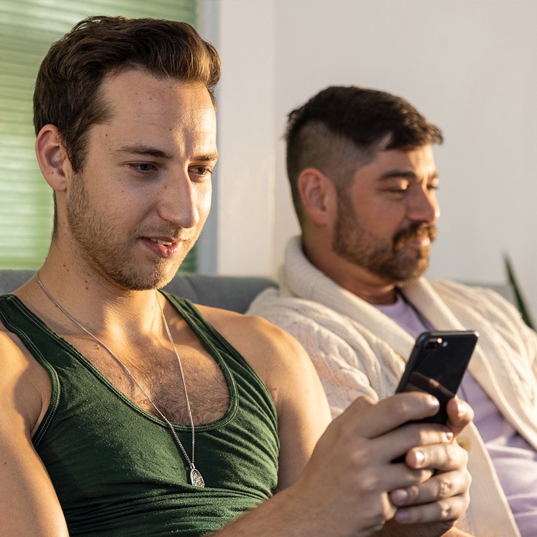 two people on a couch, one browsing their phone