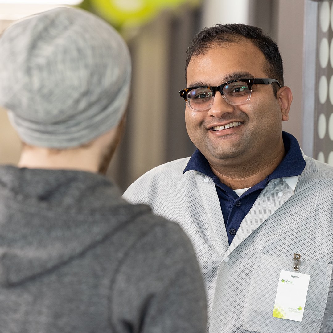 a person in a white coat and a grey hat talking to a person