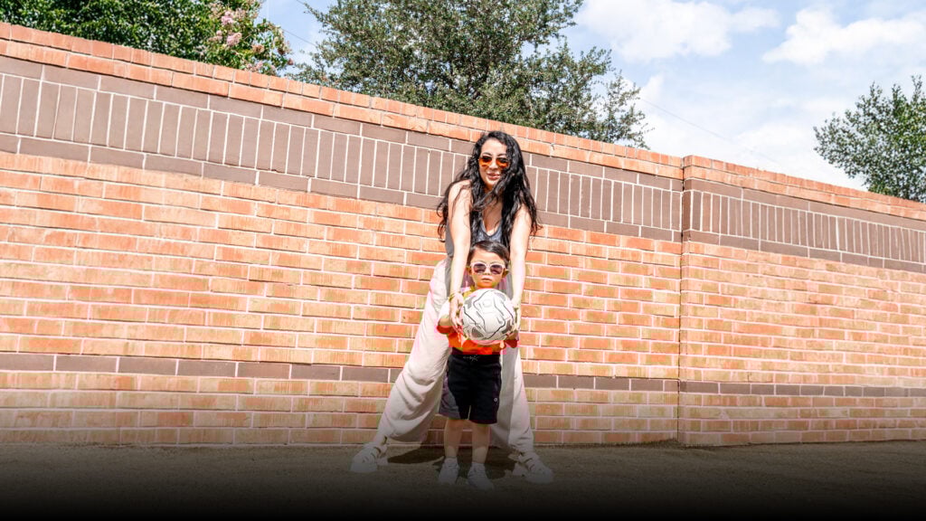 child holding soccer ball with mom behind them
