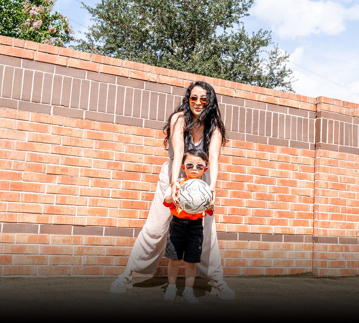 child holding soccer ball with mom behind them