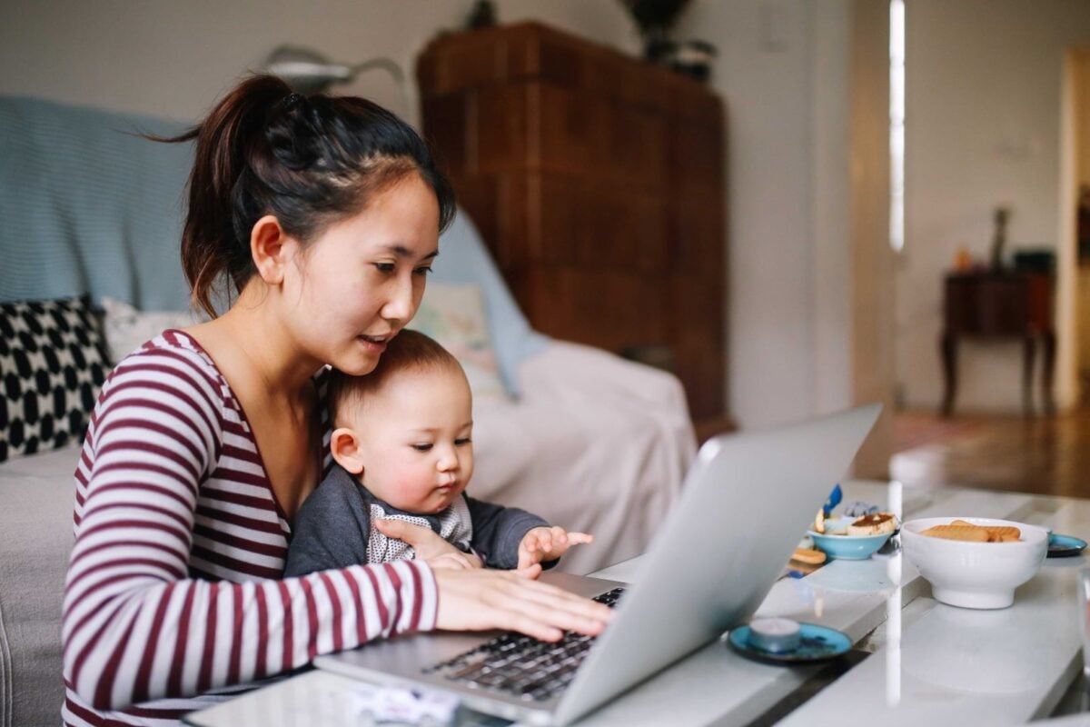 Mother researching online while holding baby.