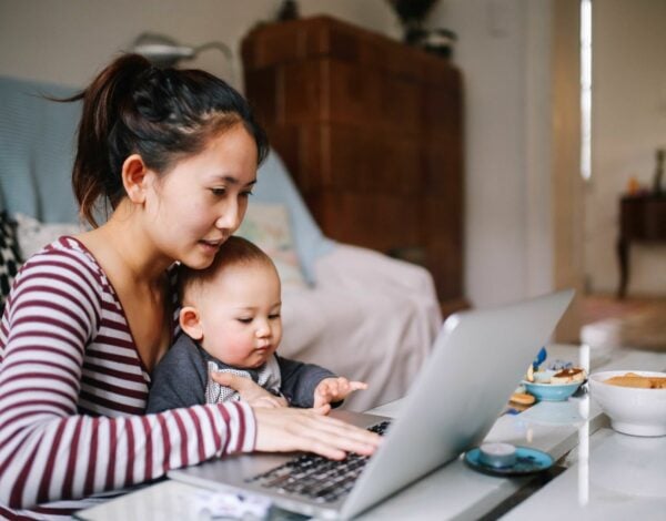Mother researching online while holding baby.