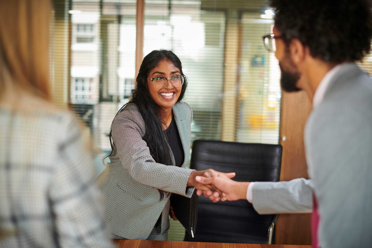 Woman on an interview shaking hands with a man.