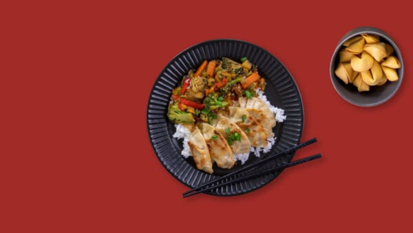 A plate of glorious food on a red background with chopsticks.