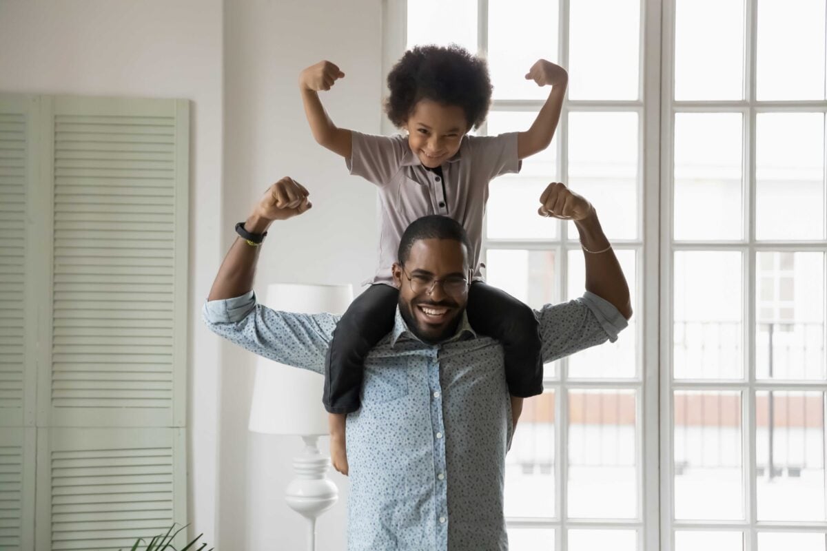 Man with child on shoulders flexing