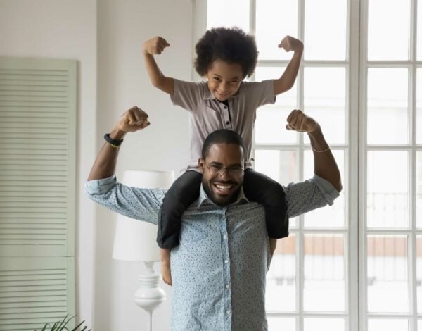Man with child on shoulders flexing